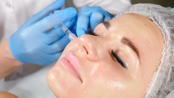 Yong female client getting face beauty injection. Woman in modern healthcare clinic getting face anti-wrinkle procedure. Non-surgical anti-aging rejuvenation. Doctor holding syringe with medication — Stock Video