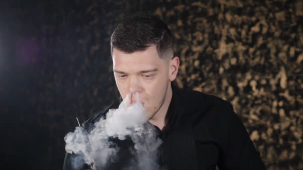 Portret przystojnego młodego kaukaski facet palenia fajki i pierścienie dymu w ciemnym pomieszczeniu. Magia sztuki mgła, Bad habbits. Brutalny człowiek relaks w barze Hookah. Zwolnionym. Hd — Wideo stockowe