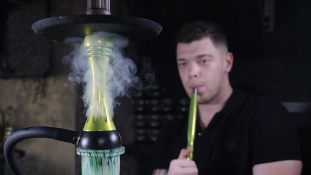 Shisha-Bar. Mann raucht Shisha und atmet Rauch ein. vape. Zeitlupe. Kaukasischer ehrfürchtiger Mann bläst Rauch. Zauberkunstnebel, schlechtes Habitus-Konzept. Zeitlupe. hd — Stockvideo