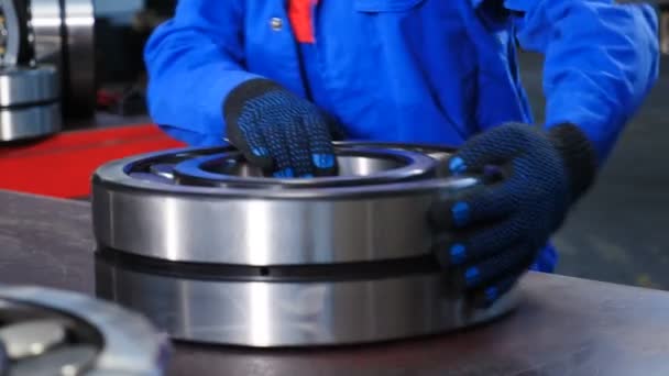 Machinery and industry concept. Set of various gears and ball large bearings, spare parts warehouse. Male worker hands in blue uniform in bearing factory. Mechanic assembles bearings. A qualified — Stock Video