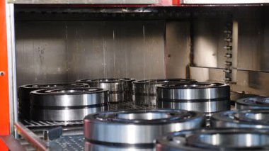Endüstriyel ve makine konsepti. Rulman üretiminin ve montajın teknolojik bir parçası. Rulman fabrikasında konveyör. Hazır öğeler hareketli teknoloji hattında motor yağı ile dökülmektedir. Yakın