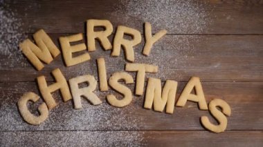 Mutlu yeni yıl kavramı. Kahverengi ahşap arka planda çerezler harfleri ile yazılmış Merry Noel notu. Yavaş hareket halinde düşen beyaz toz. Hd