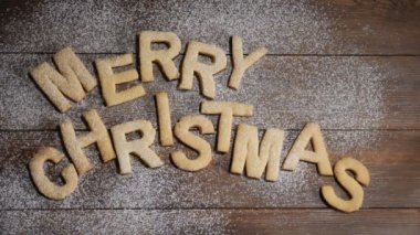 Mutlu yeni yıl kavramı. Kahverengi ahşap arka planda çerezler harfleri ile yazılmış Merry Noel notu. Yavaş hareket halinde düşen beyaz toz. Hd