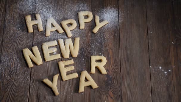 Happy New Year cookies on the brown wooden board with blank space for notes. Feast and holiday concept. White sugar powder falling down in slow motion. hd — Stock Video