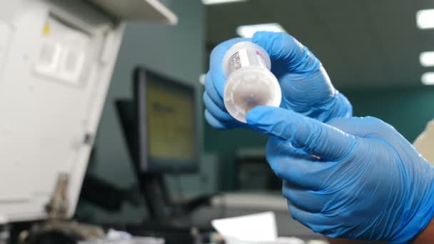 Alcance biológico do laboratório médico. Mãos em luvas azuis, segurando um tubo médico com biomaterial para análise. Teste de sangue. Parem a propagação da SIDA. Conceito de saúde e bem-estar. 4k — Vídeo de Stock