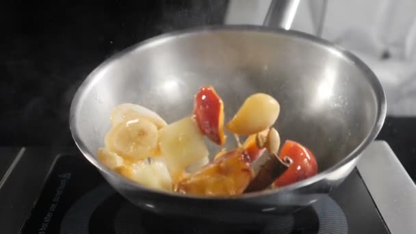 フルーツとフランベデザートを調理:バナナ、アプリコット、桃。シェフがかき混ぜて、キャラメルフルーツでフライパンをかき混ぜる。おいしいデザートのためのロースト食材。スローモーション。Hd — ストック動画