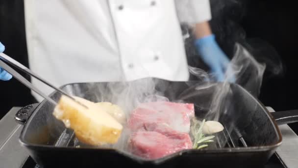 Chef cocinando patata con carne a la parrilla. Mano Usando Pinzas Para Girar Patatas en Barbacoa. Fuma en cámara lenta. hd — Vídeos de Stock