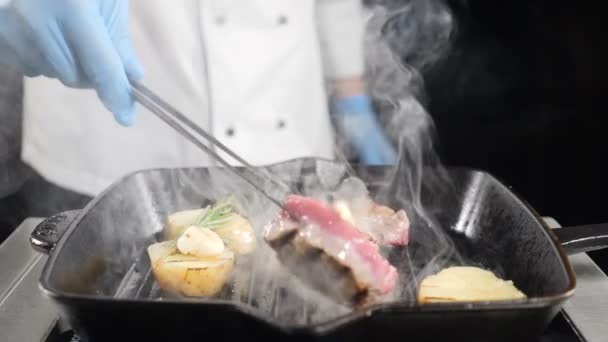 慢动作食物视频。厨师在手套使用钳子在烧烤或烧烤时把肉翻。餐厅烹饪食品。展示厨房。高清 — 图库视频影像