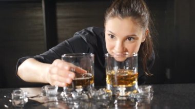 Neşeli kadın barmen bir şarap bardağından ışığa bakarak gülümsüyor. Bar tezgahında çekici kız gülümsüyor. Yavaş çekim. Hd