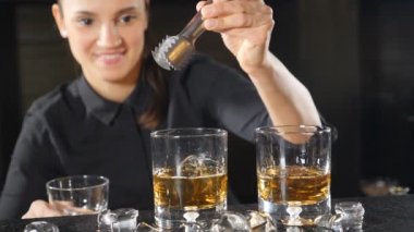 Bar konsepti. Kadın barmen barmen garson yavaş hareket te buz küpü bırakarak alkol kokteyl hazırlanıyor. samimi gülümseyen hizmet barmen içecek içecek closeup yapma. ön görünüm. Hd