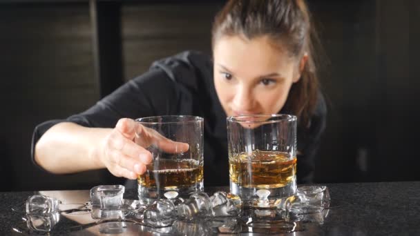 La vie nocturne dans un club. Barman féminin préparant des cocktails alcoolisés dans des verres à vin mettant des cubes de glace au ralenti. La glace tombe avec des éclaboussures. hd — Video