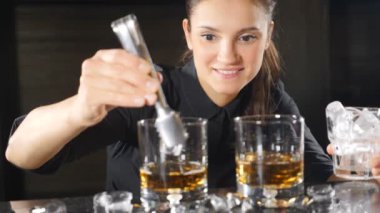 Kadın barmen barmen garson yavaş hareket te buz küpü bırakarak alkol kokteyl hazırlanıyor. samimi gülümseyen hizmet barmen içecek içecek closeup yapma. ön görünüm. Hd