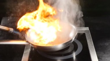 Restoran mutfağında şef pişirme flambe çanak. İtalyan mutfağı. Yavaş çekimde yemek videosu. Tava üzerinde muhteşem alev. Flambe meyve tatlısı. Hd