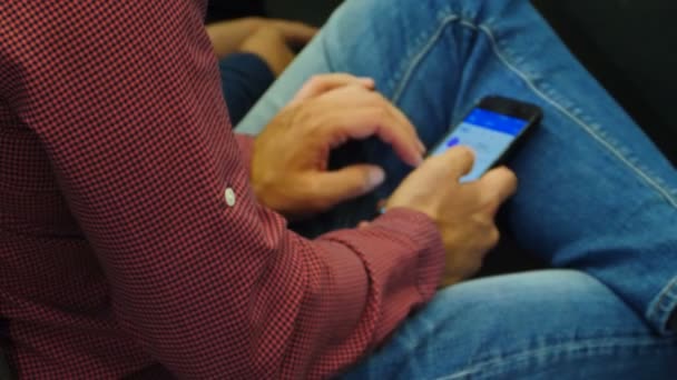 Primer plano del hombre con camisa de cheque que sostiene el desplazamiento del teléfono móvil en la reunión de negocios, conferencia de negocios o presentación, taller. audiencia en el seminario, mensajes de texto SMS. 4k — Vídeos de Stock