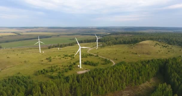 Luchtfoto van windmolens die met windkracht draaien en hernieuwbare energie opwekken. Natuur vriendelijke energie in Rusland. Drie moderne windmolens werken op veld in de late zomer. 4k — Stockvideo