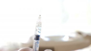 Kapalı ışık pencere arka plan ve güneş ışığı karşı püskürtme şırınga tutarak kadın el kapatın. Meslek kavramı, tıp, sağlık. 4k