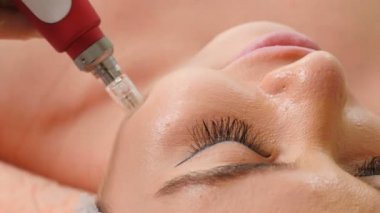 Güzellik kliniği konsepti. Profesyonel kozmetolojist Dermapen prosedürünü gerçekleştirir. yüz maskesi uygulayarak . 4k'da çekilmiş