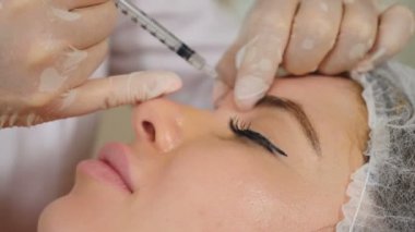 Güzellik enjeksiyon prosedürü. Genç ve güzel ciltler için yüz enjeksiyonu ve yaşlanmayı önleme prosedürü. Kozmetik kliniğinde güzellik iğnesi yaptıran bir kadın. 4K 'da çekilmiş.