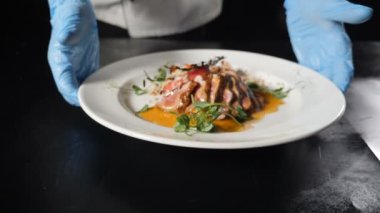 Restoran şefi, sulu dilimlenmiş et ve tatlı soslu sebzelerle hazır yemek sunuyor. Güzel yemekler, masaya tabak koymak, yemek pişirme videosu. Hd