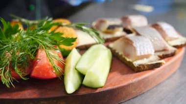 Yemek servisi konsepti. Eldivenli şef kızarmış ekmeğin üzerine paslanmaz maşayla doğranmış ringa balığı koyuyor. Lezzetli abur cuburlar. 4K 'da çekilmiş.