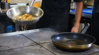 Restoran mutfağı konsepti çok yoğun. Aşçılar ve mutfak personeli ticari mutfakta yemek hazırlayıp servis ediyor. Acele et. Kapatın. Fırlatma ve kızartma tavası. 4K 'da çekilmiş.
