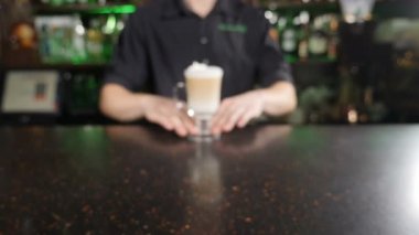 Erkek baristanın elinde pipetle hazır aromatik bir latte tutarken yakın plan. Barmen kahve yapıyor. Katmanlı kahve içeceği. Ağır çekim. Yüksek çözünürlüklü çekim