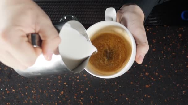 Imagens de close-up de barista derramando leite em copo, fazendo cappuccino, Bartender prepara uma xícara de cappuccino e desenha padrão de leite. conceito de loja de café. câmara lenta. hd — Vídeo de Stock