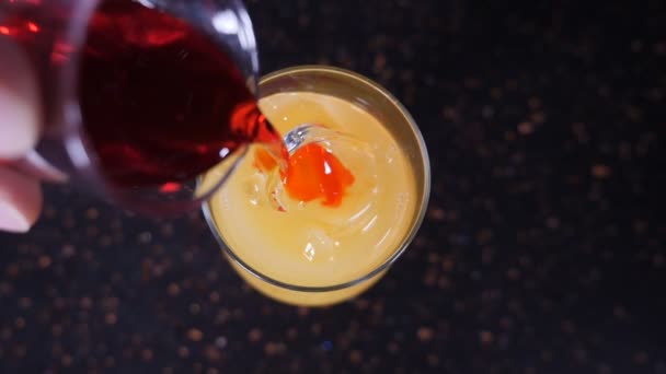 Vue de dessus. Barman versant du liquide pour préparer un cocktail sur le comptoir du bar noir. Le barman prépare une boisson lumineuse dans le bar de la boîte de nuit. Au ralenti. hd — Video