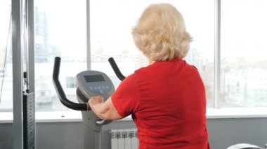 Beden eğitimi dersinden emekli bir kadın kardiyo egzersizi yapıyormuş. Sağlıklı ve aktif yaşlı bir kadın. Aktif son sınıflar. Spor salonundaki yaşlı kadın. 4K 'da çekilmiş.