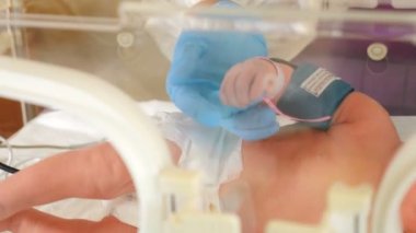 Doğum kliniği. Hayat kurtarıyorum. Hemşire bir bebeği kuluçka makinesinde muayene ediyor. Hastanede beşiğin içinde yatan yeni doğmuş bir bebek. 4K 'da çekilmiş.