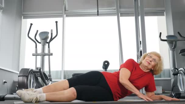 Mode de vie sain dans la vieillesse. Déterminé souriant femme caucasienne senior faisant de l'entraînement sportif dans un studio de fitness. Concept de motivation. 4k — Video