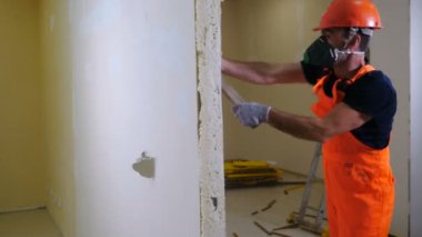 Üniformalı ve solunum cihazlı işçiler iç duvar balyozu patlatıyor. Yıkım işi ve yeniden düzenleme konsepti. Alçı taşı kartonunun yok edilmesinden oluşan duvar. 4k video