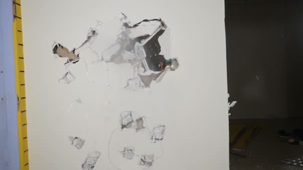Zeď ze sádrovcové lepenky byla zničena. Pracovník v uniformě ničí kladivo na vnitřní stěnu. Demoliční práce a koncepce přeskupení. Zpomal. Full hd — Stock video