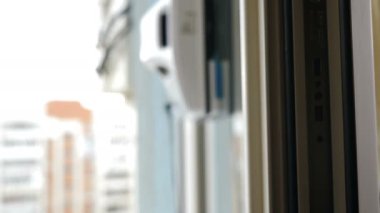 Pencere temizleme robotu iş başında. Ev hizmeti ve temizlik konsepti. Küçük beyaz cam yıkama makinesi daire pencerelerinde hareket ediyor ve dönüyor. Modern akıllı cam temizleyicileri. 4k
