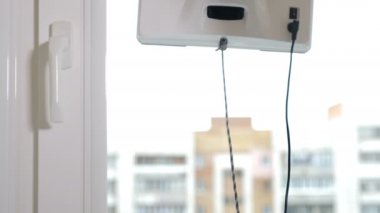 Temizlik servisi. Küçük beyaz cam yıkama makinesi daire pencerelerinde hareket ediyor ve dönüyor. Modern akıllı cam temizleyicileri. 4k