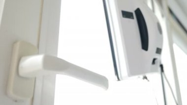 Window cleaning robot, Close-up shot. Robot square window glass washer moving on window. Small robot glass washer cleaning window in apartment. Contactless glass washer machine. 4k video