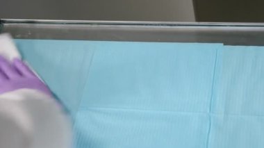 Antibakteriyel alkol peçetesiyle silme masası. Klinikteki yüzeylerin temizlenmesi ve dezenfekte edilmesi. Dezenfekte edilebilir ıslak mendiller. Tıbbi eldivenli eller beyaz silme yüzeyi. Önleme ve kontrol
