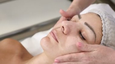 Sağlık ve güzellik salonu. Rahatlatıcı ve sağlıklı. Spa kadını yüz masajı. Kadın kozmetik merkezindeki yüz masajından zevk alıyor. Vücut bakımı, cilt bakımı, güzellik tedavisi. 4k video