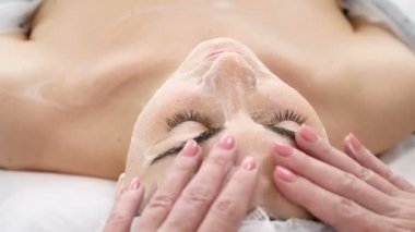 Sağlık ve güzellik salonu. Rahatlatıcı ve sağlıklı. Spa kadını yüz masajı. Kadın kozmetik merkezindeki yüz masajından zevk alıyor. Vücut bakımı, cilt bakımı, güzellik tedavisi. 4k video