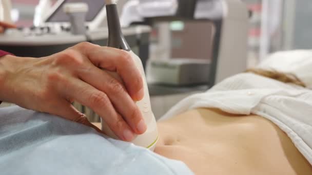 Hälsoskydd. Närbild skott av kvinnlig läkare gör ultraljud av magen. Kvinnlig patient på kliniken. Medicinsk undersökning av buken med ultraljudsanordning. 4 k-film — Stockvideo