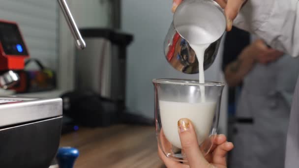 Proceso de elaboración de café. Barista cocinar café y vierte la leche caliente gruesa y fresca en taza transparente. Primer plano de barista vertiendo leche para hacer Latte. En cámara lenta. Full hd — Vídeos de Stock