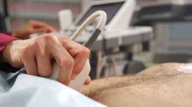 Sağlık sigortası konsepti. Erkek sağlığı. Doktor elin prostat için ultrason çekerken yakın çekim. Hastanede ultrasonografi. Erkek hasta ultrason taraması yaptırıyor. 4k video