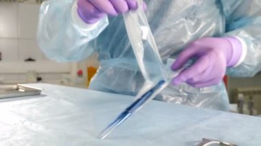 Diş cerrahisinde hazırlık. Asistan masasına yerleştirilmeden önce cerrahi aletler açılıp yerleştirildi. Kadın asistanın implantasyona hazırlandığı yakın çekim. 4k görüntü