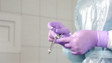 Diş hekiminin şırıngayı hazırlarken ve ampulü yerleştirirken yakın plan fotoğrafı. İlaç, dişçi ve sağlık hizmeti konsepti. Eldivenle dişçi elinde anesteziyle şırınga tutuyor. 4k video