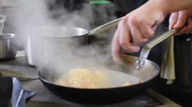 Kızartma tavasında kremalı spagetti pişirip karıştırmak, yakın çekim. Yemek videosu. Lezzetli bir aşçı. 4k görüntü