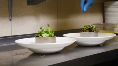 Şef restoranın mutfağında salata yapıyor. Yavaş çekim yemek videosu. Şef salataya mikro kasvetli şeyler ekliyor. Restoranlar yemek pişirme konsepti. 4k görüntü