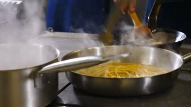 Kızartma tavasında kremalı spagetti pişirip karıştırmak, yakın çekim. Yemek videosu. Lezzetli bir aşçı. 4k görüntü