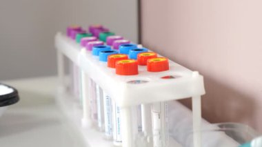 Tıp ve sağlık hizmetleri kavramı. Koruyucu laboratuvar asistanı kan testi tüpünü santrifüj edilmiş kan plazmasıyla rafa ya da tutucuya koyuyor. Modern klinikteki Genetik Araştırma Laboratuvarı. 4k video