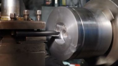 Torna torbasını devrede. Atölye dönüşümündeki eski torna makinesi keserek bir iplik üretir. İçten dokunuşlar, yakın plan. Metal Fabrikası Fabrika 'da Metal Detayı Üretiyor. 4 bin.