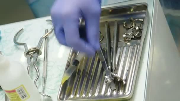 Preparazione per la chirurgia dentale. dentista scegliere e prendere strumento per il trattamento dei denti in studio odontoiatrico moderno, primo piano colpo. trapano sterile appropriato per strumento dentale. 4K filmati — Video Stock